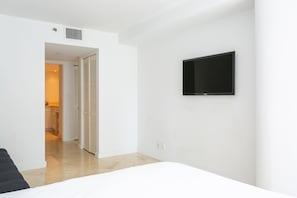 Une chambre d’hôtel avec un lit, un téléviseur fixé au mur et une porte donnant sur une salle de bain.