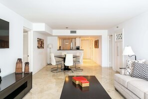 A modern living room with a dining area, kitchen, and a sofa with a patterned throw pillow.