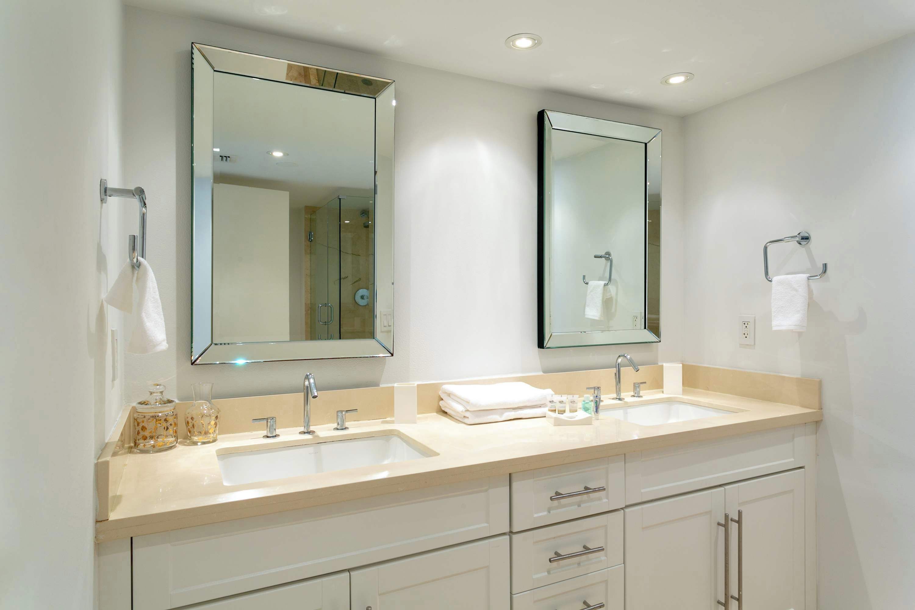 Une salle de bain moderne avec deux lavabos, un grand miroir et un meuble-lavabo avec des tiroirs.