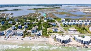 Oversigtsbillede af et kystnære boligområde med huse, en strand og et vandområde.