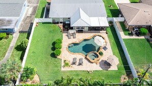 Una casa con un patio trasero amplio, piscina y zona de patio.