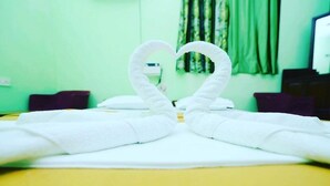 A hotel room with a bed, a heart-shaped towel arrangement, and a green wall. - Casa German Near The Beach (Calangute)