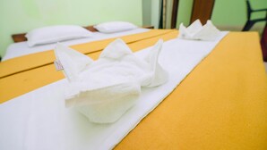 A neatly arranged bed with white towels and a yellow bedspread in a room with green walls. - Casa German Near The Beach (Calangute)