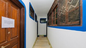 A hallway with a wooden door, a sign on the wall, and a window with a decorative pattern. - Casa German Near The Beach (Calangute)