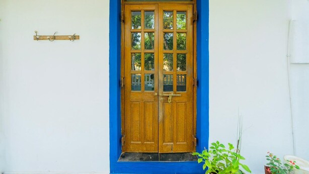 A wooden double door with glass panels, set within a blue-framed window, against a white wall. - Casa German Near The Beach (Calangute)