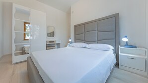 A bedroom with a large bed, a nightstand with a lamp, a wardrobe, and a mirror. - Luxury Villa on the Beach in Diamante, Sea View - Villa Ventre (Belvedere Marittimo)