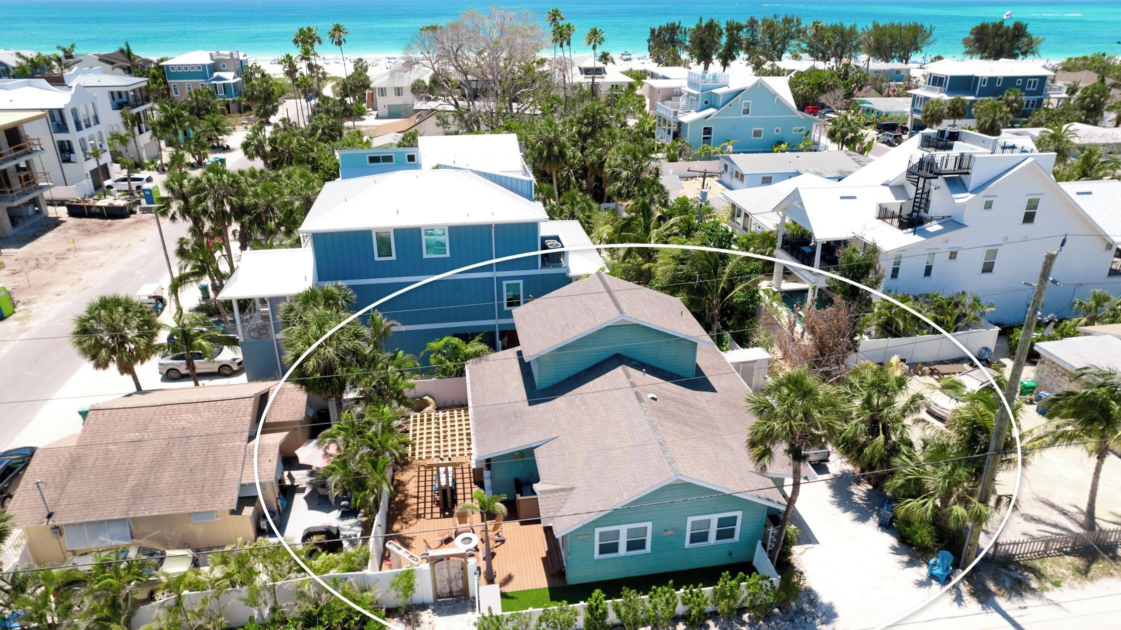 Zona residencial con casas, piscina y playa al fondo.