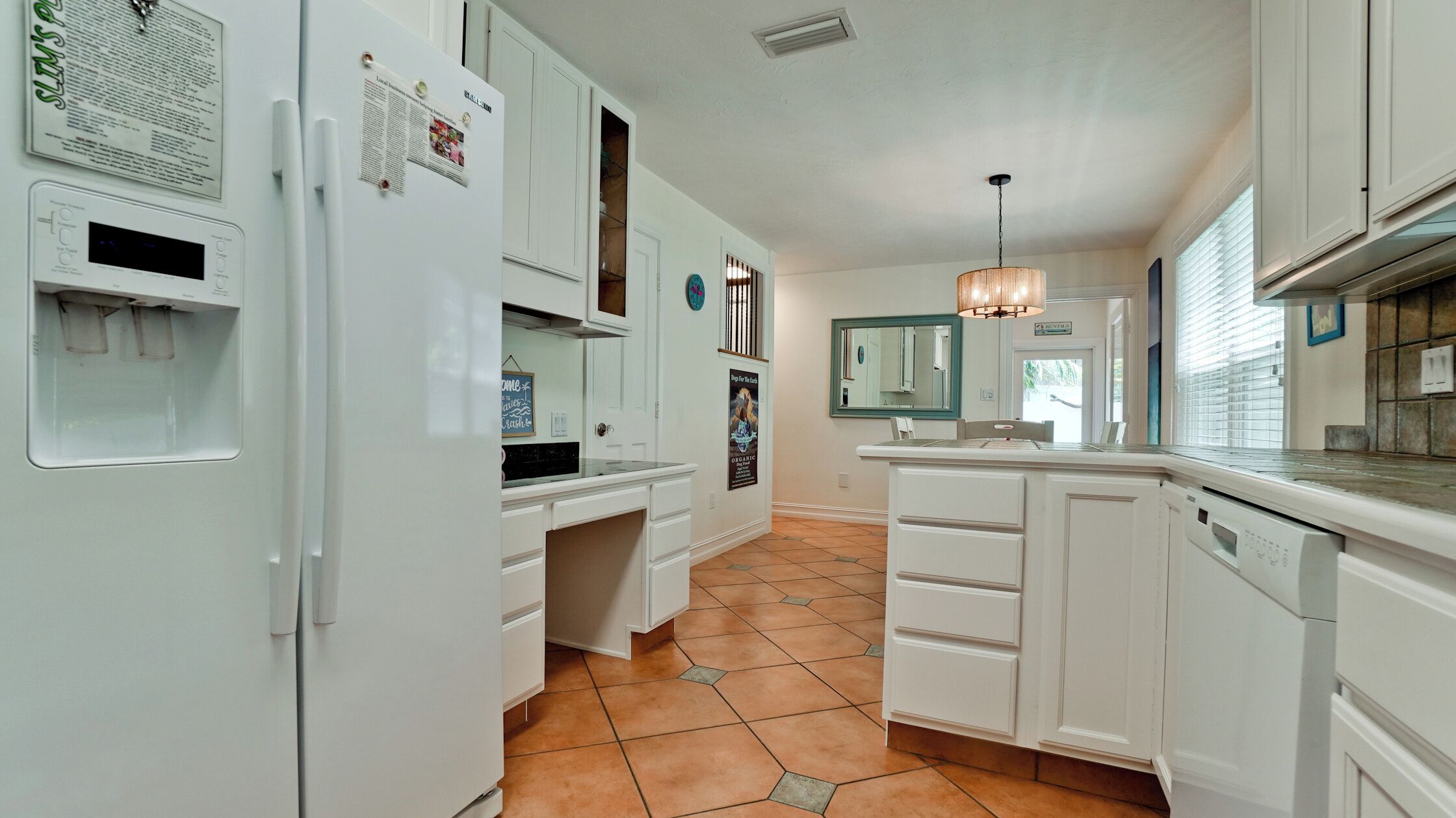 A kitchen with white cabinets, a refrigerator, a water dispenser, and a tiled floor.