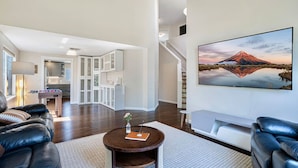 A spacious living room with a fireplace, a dining area, and a kitchen in the background. - Spacious 4BR Getaway  | Grill, Patio & Game Table (Federal Way)