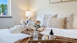 A hotel room with a bed, a tray with toiletries, a vase with flowers, and a wall with a moon and sun design. - Spacious 4BR Getaway  | Grill, Patio & Game Table (Federal Way)