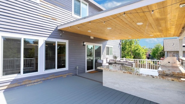 A modern house with a covered patio, large windows, and a deck. - Spacious 4BR Getaway  | Grill, Patio & Game Table (Federal Way)