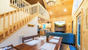A wooden interior with a dining table, benches, a staircase, and a sofa. - Couples Private Mountain Oasis!! Hot Tub! Theatre! Fire Pit! (Sevierville)