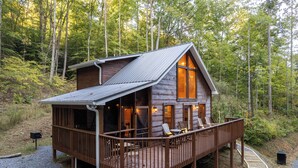 A cabin with a deck, wooden exterior, and large windows. - Couples Private Mountain Oasis!! Hot Tub! Theatre! Fire Pit! (Sevierville)