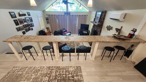 A kitchen with a granite countertop, four black stools, a rug, and a stone fireplace. - Rock Ledge at the Narrows (Higden)