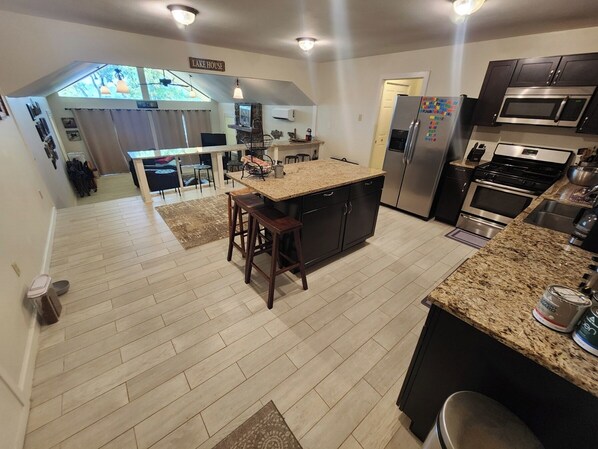 A modern kitchen with granite countertops, stainless steel appliances, and a central island with stools. - Lake Views, Water Trail and Minutes to the Marina (Higden)