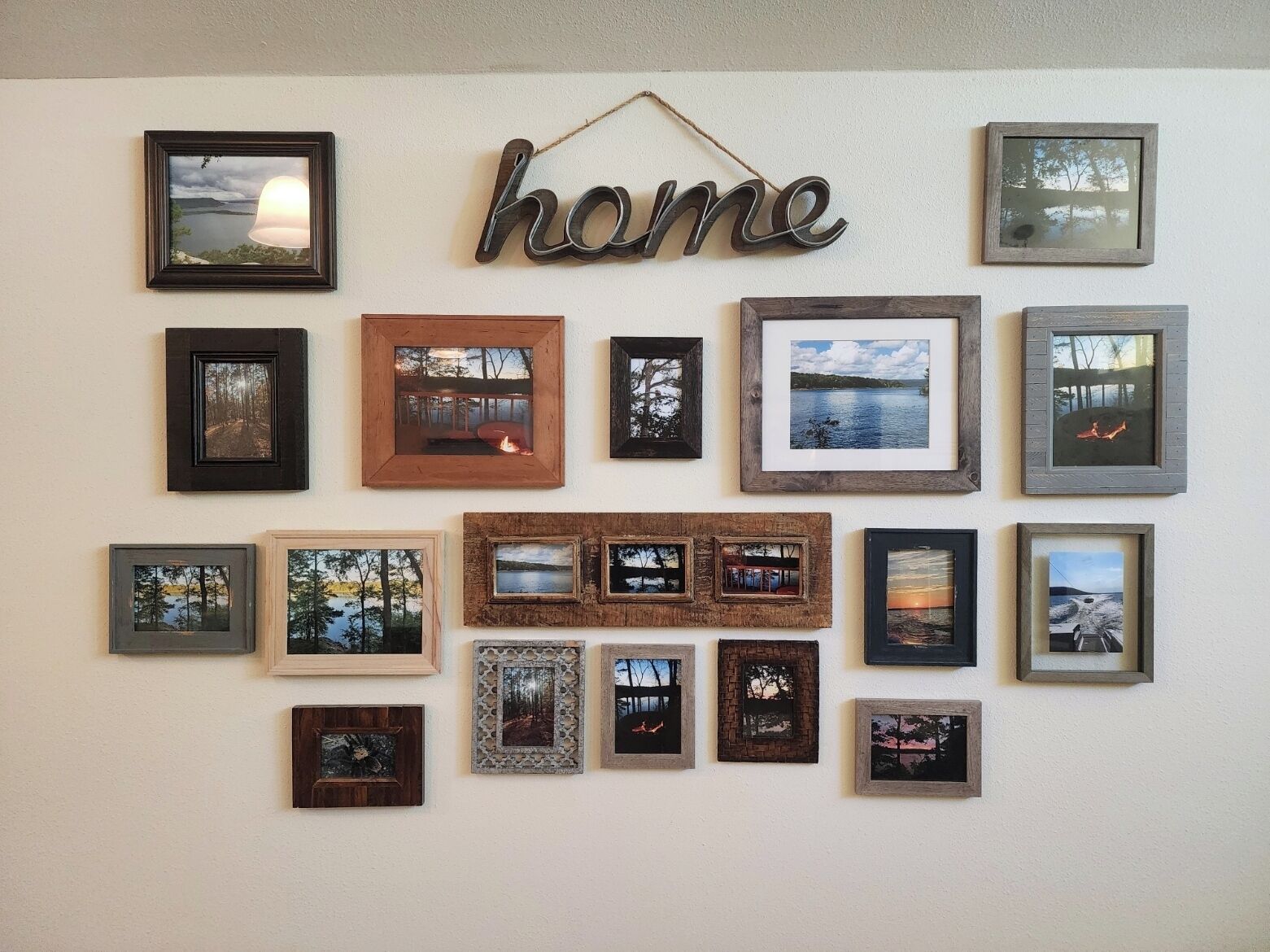 A wall with various framed photographs and a 'home' sign.