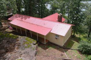 A two-story house with a red roof, surrounded by trees and a body of water. - Lake Views, Water Trail and Minutes to the Marina (Higden)