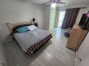 A bedroom with a bed, a ceiling fan, a TV on a wooden cabinet, and a door leading to a balcony. - Lake Views, Water Trail and Minutes to the Marina (Higden)