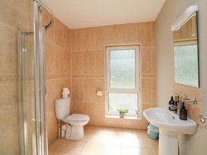 Un baño con cabina de ducha de vidrio, inodoro, ventana y lavabo.