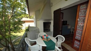 Une terrasse avec une table et des chaises, un barbecue et une vue sur une maison et des arbres.