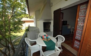 Une terrasse avec une table et des chaises, un barbecue et une vue sur une maison et des arbres.