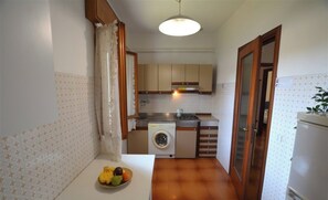 Een kleine keuken met een wasmachine, een spoelbak en een fornuis.