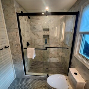 Une salle de bain moderne dotée d’une douche à parois de verre, de toilettes et d’un lavabo.