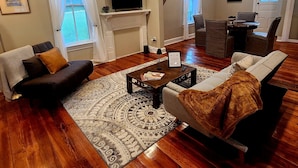 Una sala de estar con chimenea, televisor y comedor con mesa y sillas.