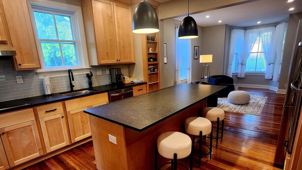 Una cocina moderna con armarios de madera, una isla grande con taburetes y una zona de bar.