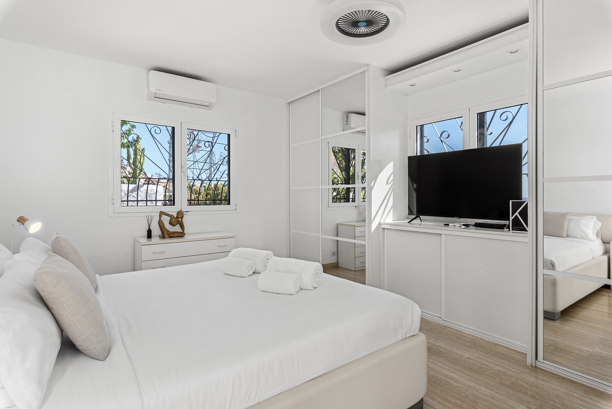 A modern bedroom with a large bed, a TV, and a walk-in closet.