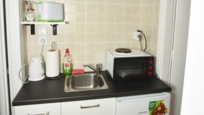 Een compacte keuken met witte kastjes, een zwart aanrecht, een magnetron, een broodrooster en een spoelbak.