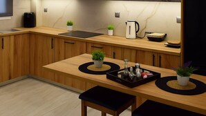 A modern kitchen with dark grey cabinets, a wooden countertop, and a black refrigerator. - Lavish Living Suite Heraklion Crete (Hersonissos)