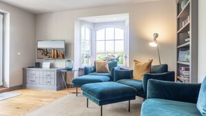 A modern living room with a grey sofa set, a coffee table, and a bookshelf.