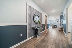 A hallway with a patterned wall, a decorative mirror, and a staircase leading to another room. - 2210 Lelani Circle (Davenport)