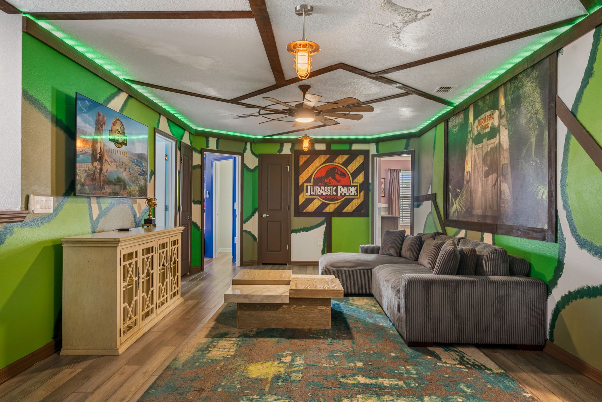 A room with a couch, a ceiling fan, and a rug.