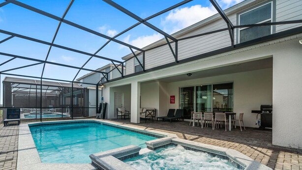 Un espace piscine comprenant un jacuzzi, des sièges extérieurs et un patio couvert.