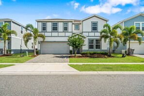 A two-story residential building with a garage, surrounded by well-maintained lawns and palm trees. - 2210 Lelani Circle (Davenport)