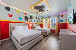 A hotel room with two beds, a ceiling fan, and Mickey Mouse-themed wall decorations. - 2210 Lelani Circle (Davenport)