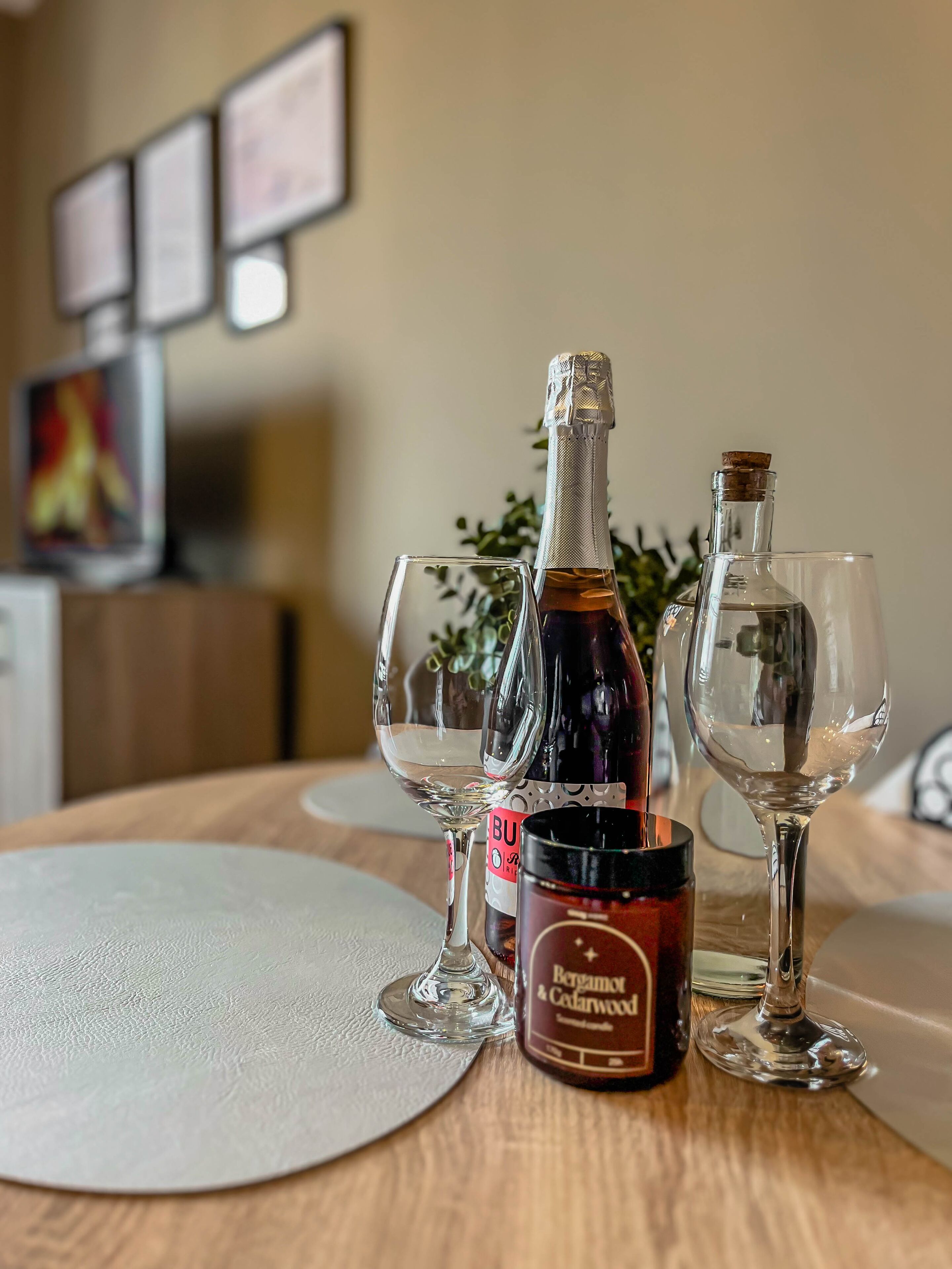 A table with a bottle of champagne, two empty wine glasses, and a candle.