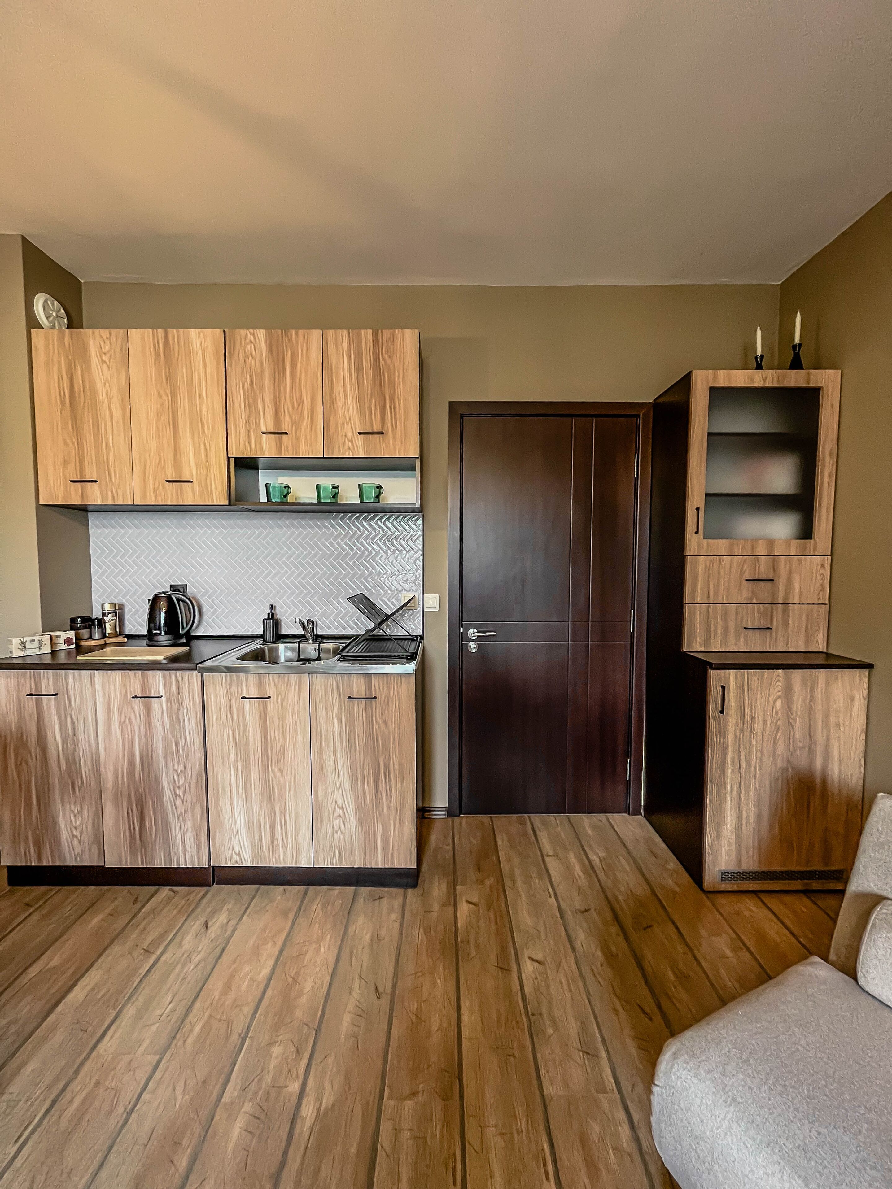 A compact kitchen with wooden cabinets, a built-in stove, and a dark door.