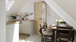 Una cocina compacta con comedor, que incluye una puerta de madera, armarios blancos y una pequeña mesa de comedor con sillas.