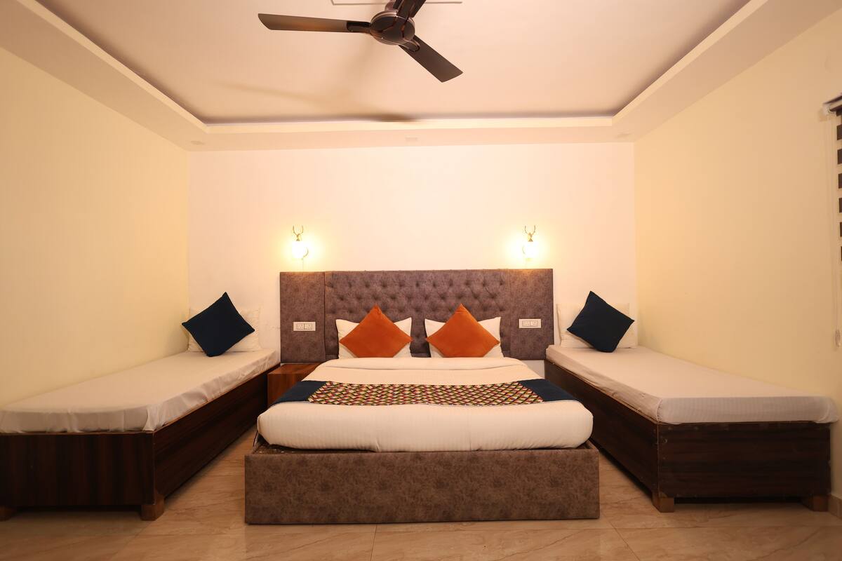 A bedroom with a large bed, two smaller beds, a ceiling fan, and wall-mounted lights.