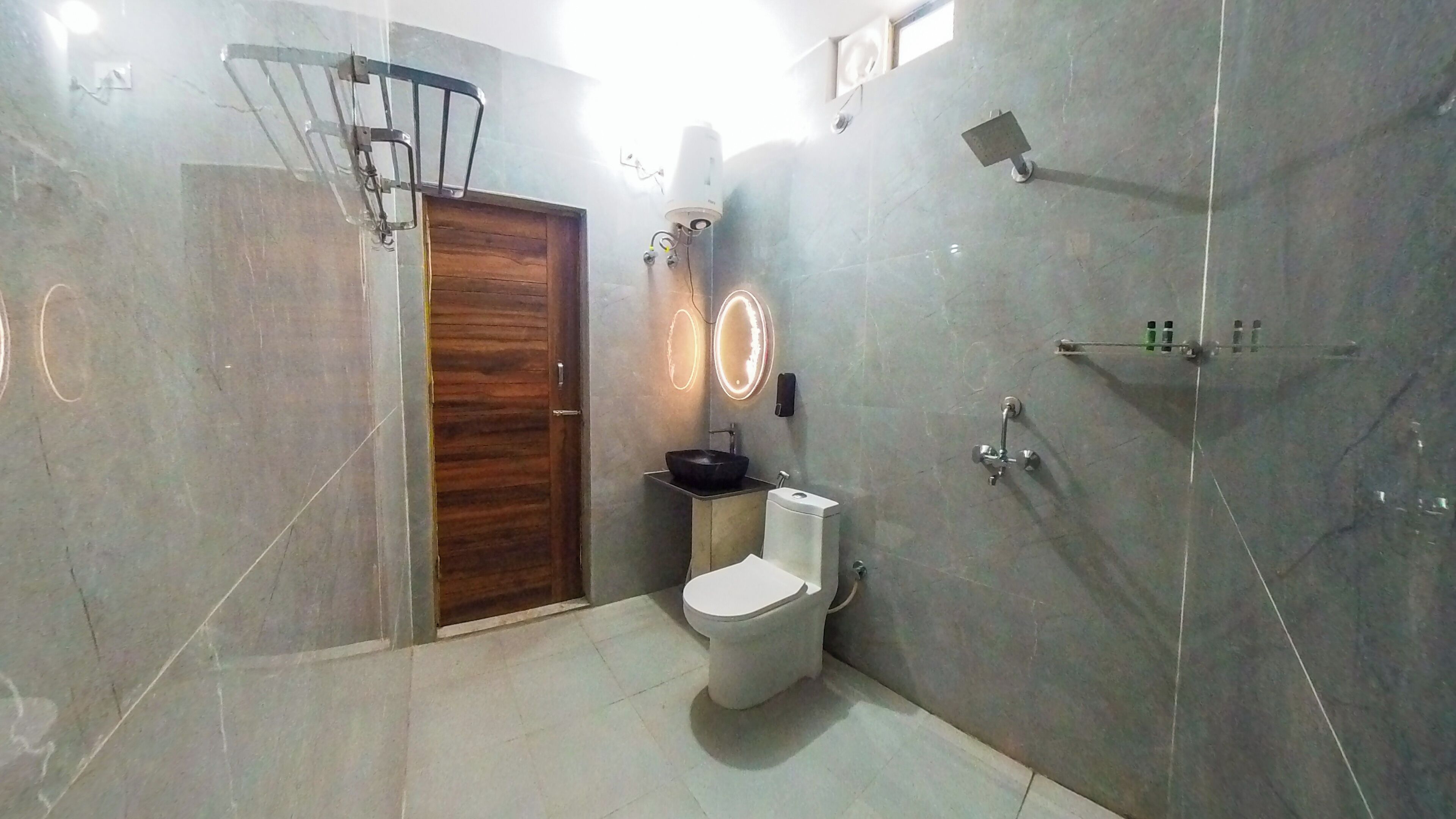 A bathroom with a wooden door, a white toilet, a black sink, and a shower area.