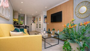 A modern living room with a yellow sofa, a coffee table, and a large plant.