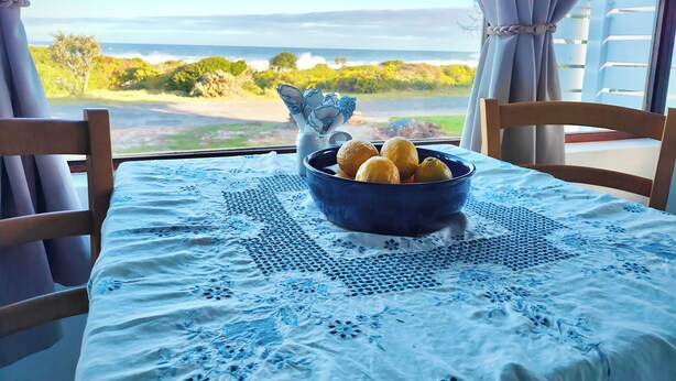 Une table recouverte d’une nappe en dentelle bleue, un bol bleu contenant des citrons et un vase décoratif.