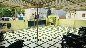 A covered outdoor area with a checkered floor, a metal gate, and parked motorcycles. - Millennium Eco Retreat (Coimbatore)