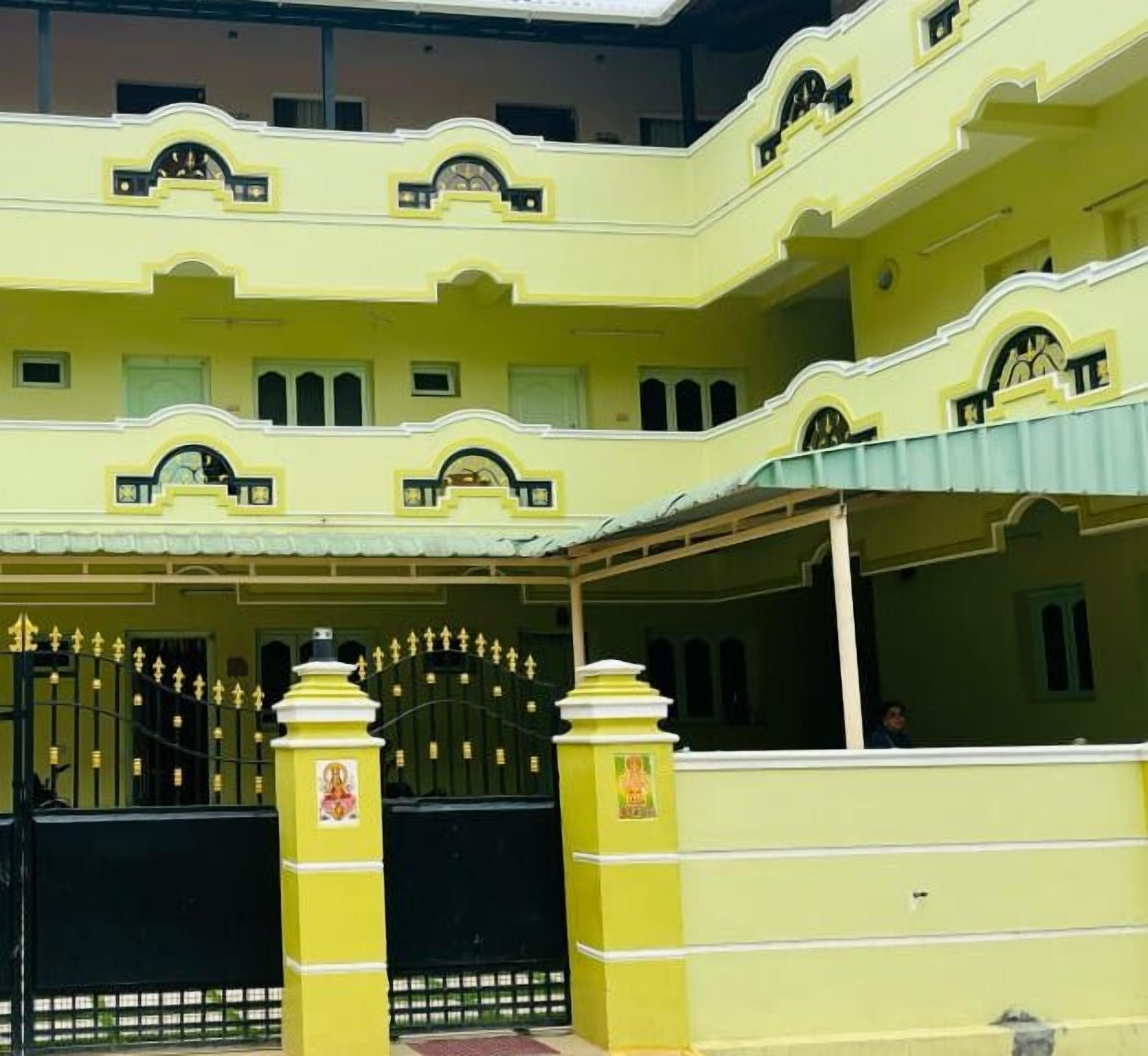 A multi-story building with a yellow facade, a gated entrance, and a covered porch area.