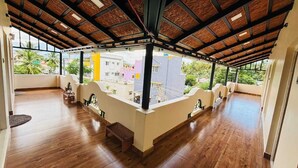 A spacious balcony with wooden flooring, a wooden ceiling, and a view of buildings and greenery. - Millennium Eco Retreat (Coimbatore)