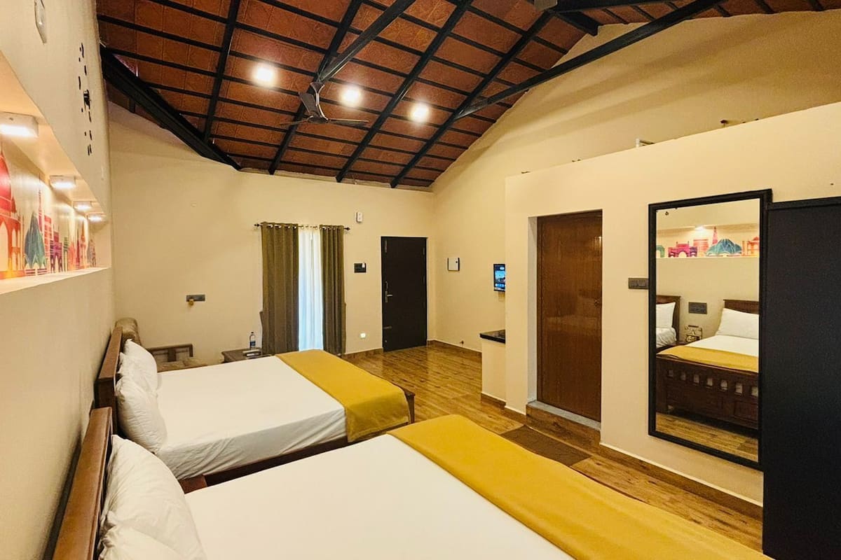 A hotel room with two beds, a wooden floor, a ceiling fan, and a large mirror on one wall.