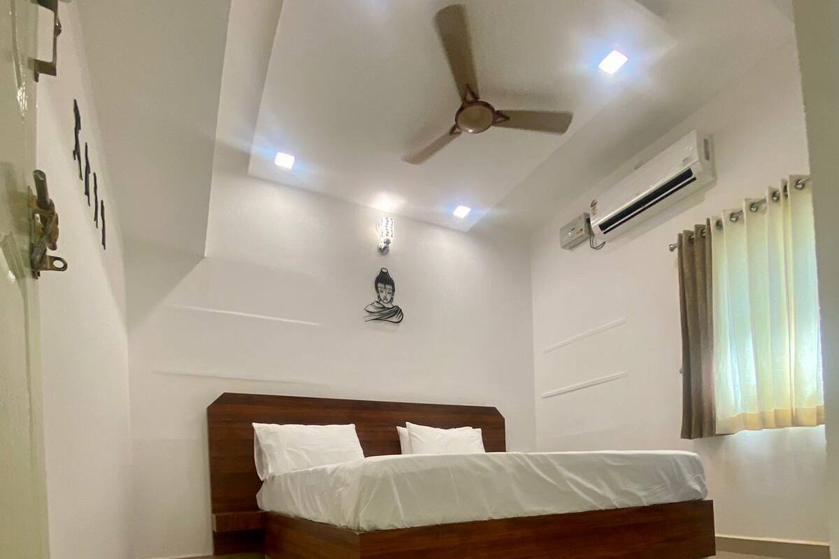 A bedroom with a wooden bed, white walls, a ceiling fan, recessed lighting, and an air conditioning unit.